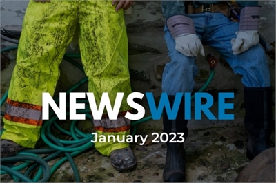 [ai] Two individuals sitting side by side on a surface with green garden hoses nearby. One person wears bright yellow waterproof pants and rubber boots, while the other is in blue jeans and black boots, both with gloves on.